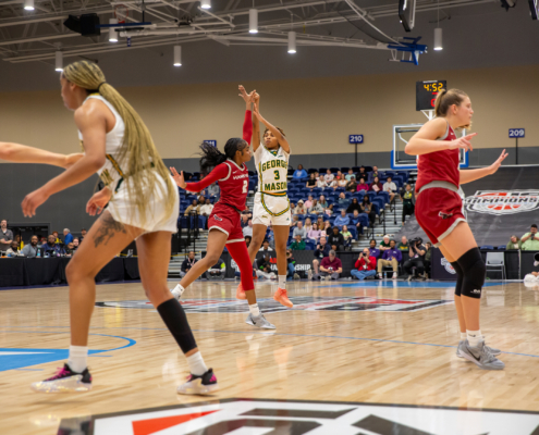 A10 basketball game with a player from George Mason shooting from the 3-point line against St. Joseph's